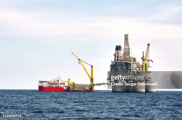boren rig en ondersteuning vaartuig op offshore gebied - bouwplatform stockfoto's en -beelden