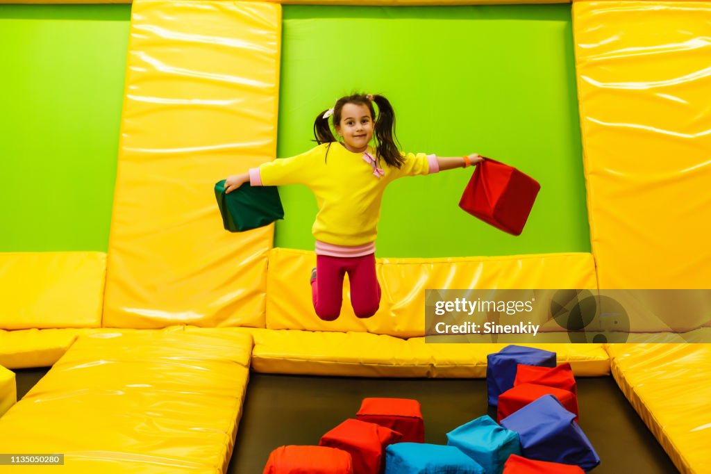 Happy childhood of a modern child in the city - girl jumping in the trampoline park