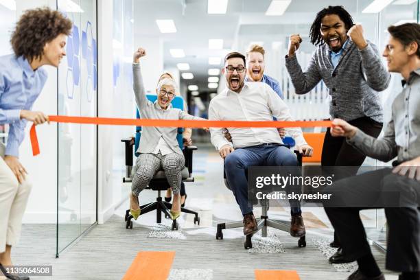 grote groep van vrolijke collega's die plezier hebben tijdens de stoel race in het kantoor. - business people cheering in office stockfoto's en -beelden