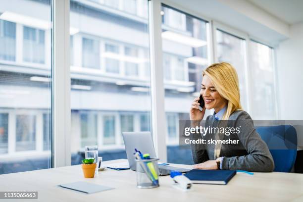 glückliche geschäftsfrau spricht auf dem handy, während die arbeit am laptop im büro. - telefonberatung stock-fotos und bilder