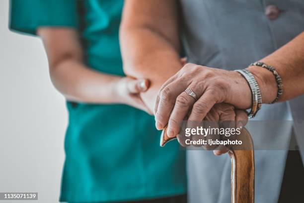 close-up of elderly woman holding walking stick in the nursing house - grandma cane stock pictures, royalty-free photos & images
