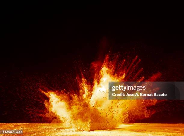 explosion by an impact of a cloud of particles of powder and smoke of color yellow and orange on a black background. - bom stockfoto's en -beelden