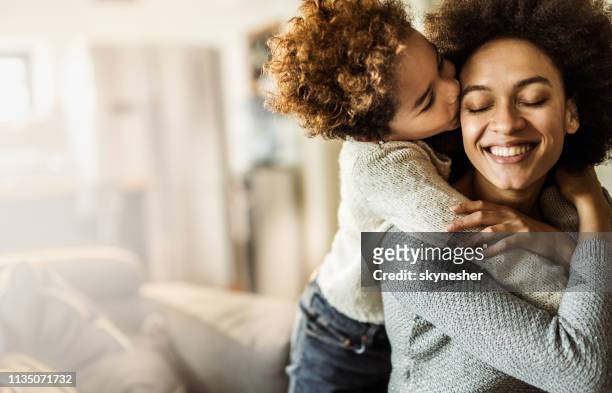 aanhankelijk afro-amerikaanse dochter zoenen haar moeder thuis. - friends kissing cheeks stockfoto's en -beelden