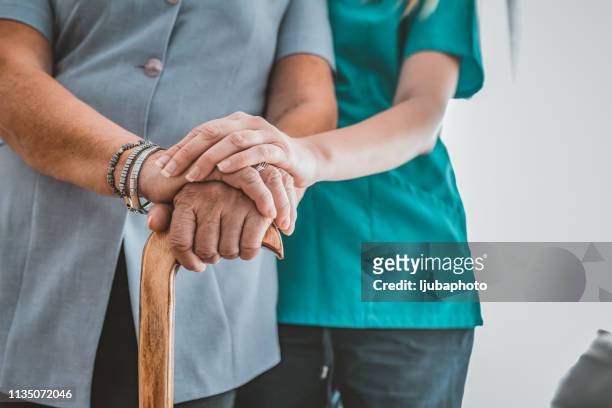 friendly caregiver helping senior woman with walking stick - grandma cane stock pictures, royalty-free photos & images