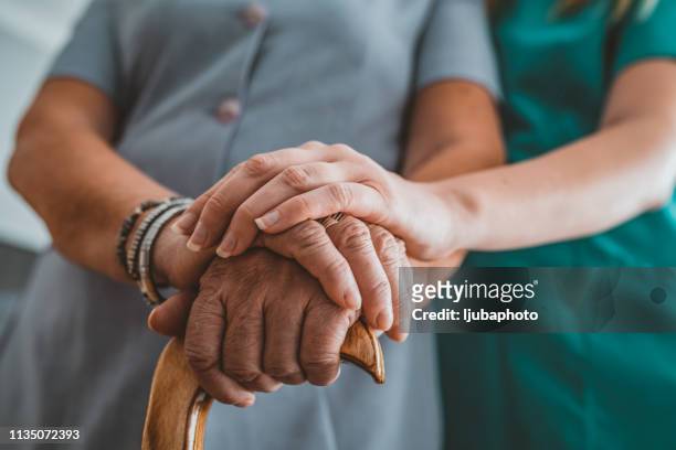 young woman holding hand of old woman with walking stick during the day - grandma cane stock pictures, royalty-free photos & images