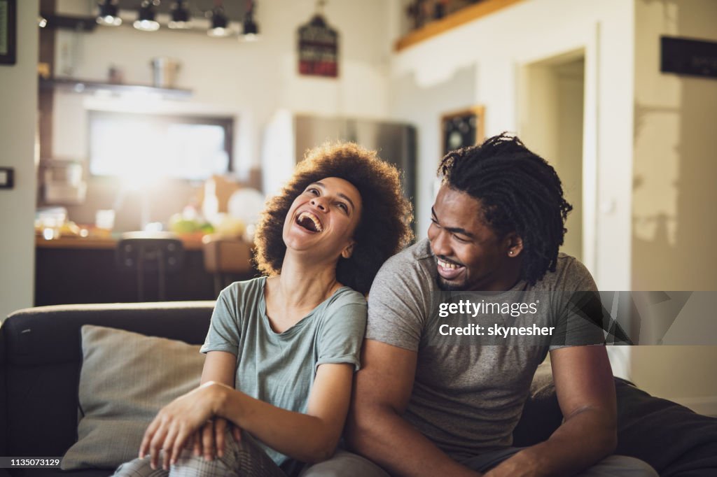 Young cheerful African American couple in the living room.