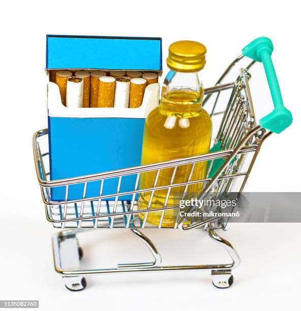 close-up of alcohol bottles and cigarette in shopping cart - cigarette pack stock pictures, royalty-free photos & images