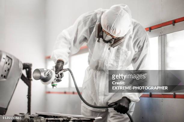 car painter in white overalls spraying a small car part with paint - spray booth stock pictures, royalty-free photos & images