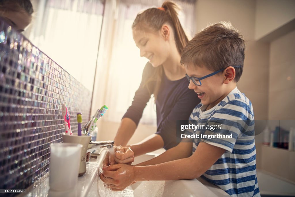 Hermano y hermana divirtiéndose lavarse las manos