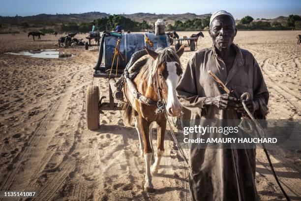 Hawker looks on after filling barils with water in the wadis Moura in Hadjer Hadid, in the Ouaddaï region, in eastern Chad, on March 24, 2019. -...