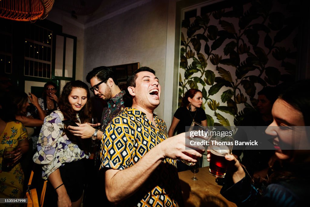Laughing friends toasting during party in night club