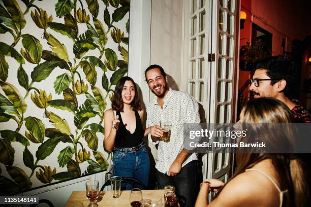portrait of laughing couple at party with friends in night club - elegant man night stock-fotos und bilder