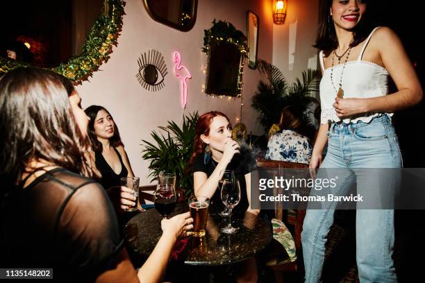 woman smoking electronic cigarette while hanging out with friends in night club - 電子タバコ ストックフォトと画像