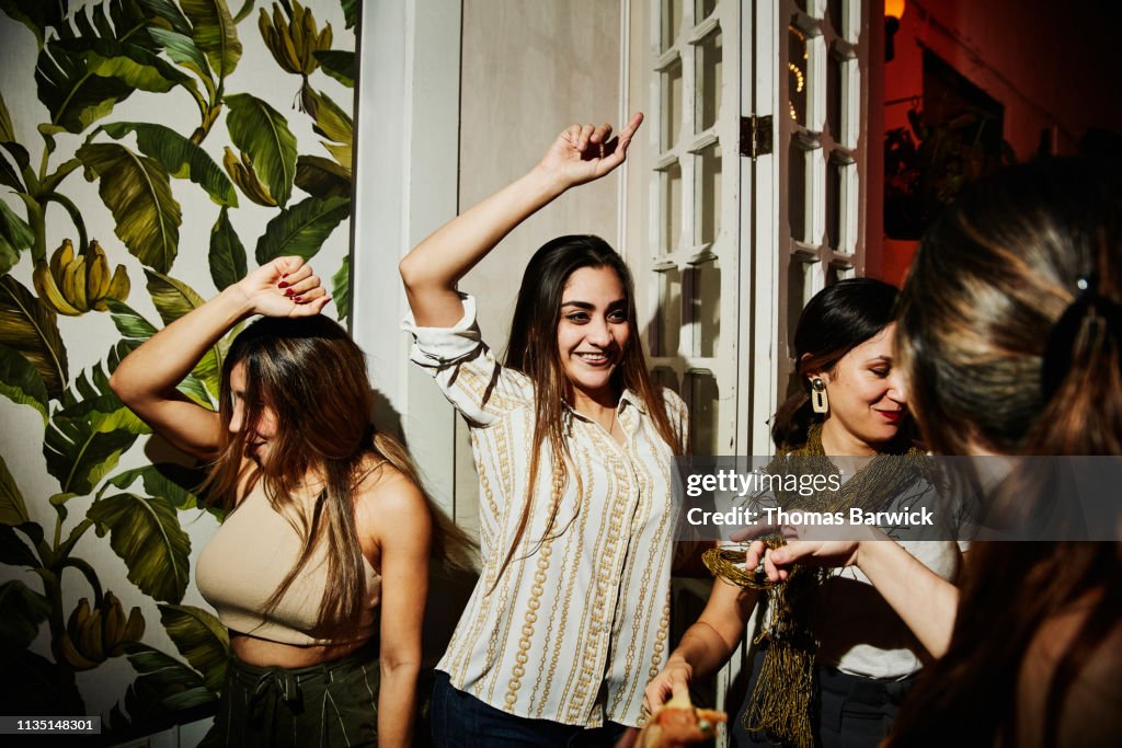 Smiling female friends dancing together during party in night club
