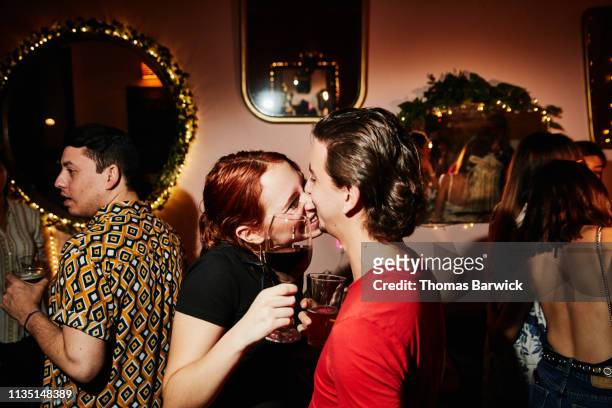 Laughing couple kissing while on date in night club