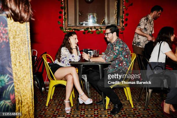 smiling couple in discussion while seated at table in night club - dating stock-fotos und bilder