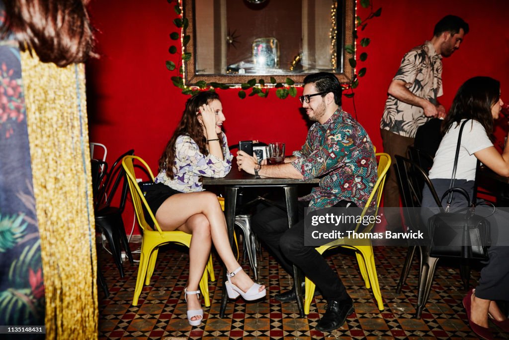 Smiling couple in discussion while seated at table in night club