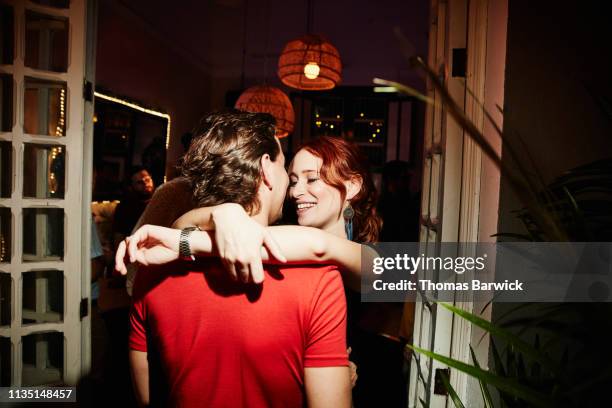 smiling woman embracing boyfriend during party in night club - romantiek stockfoto's en -beelden