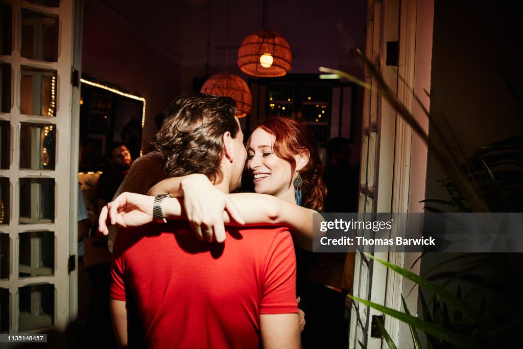 Smiling woman embracing boyfriend during party in night club