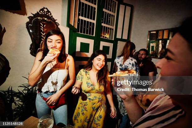 laughing female friends enjoying food during party in night club - mexican food stock-fotos und bilder