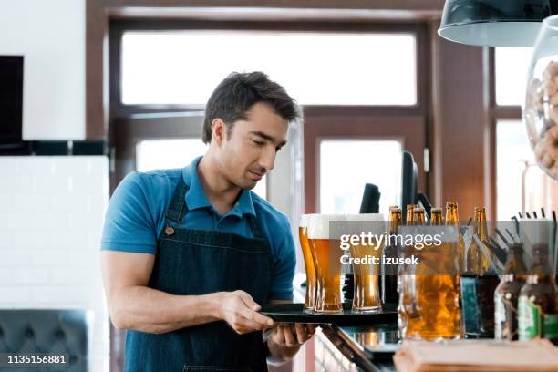 bartender trägt gläser bier auf tablett in der kneipe - kellner tablett stock-fotos und bilder