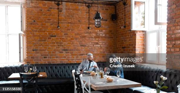 entrepreneurs discussing while having lunch in pub - brick wall business person stock pictures, royalty-free photos & images