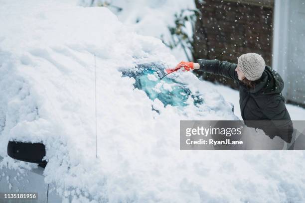 woman scraping snow and ice off car windshield - auto mieten stock pictures, royalty-free photos & images