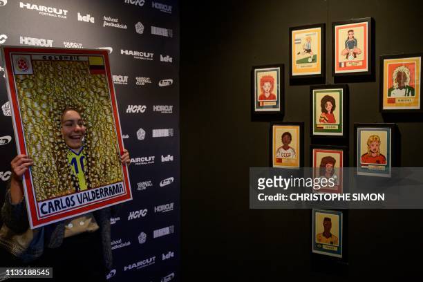Visitor poses for a picture passing her face through a hole in a painting depicting Colombian former footballer former Carlos Valderrama during the...