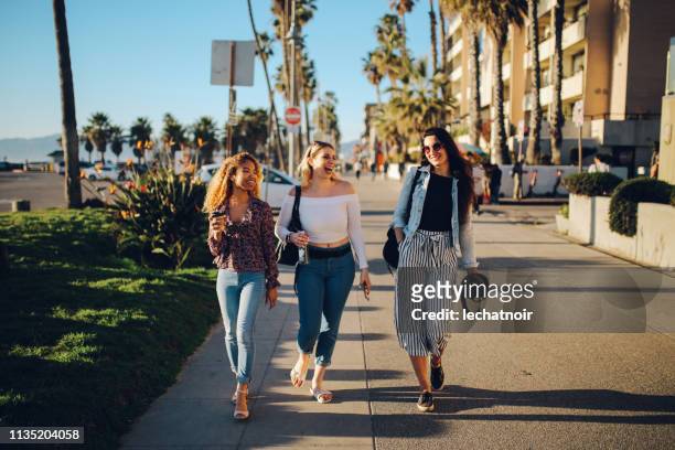 young female friends enjoying the walk on the venice beach in la, california - a la moda stock pictures, royalty-free photos & images