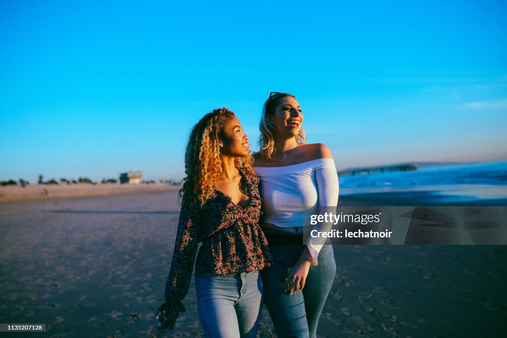 Jóvenes amigas disfrutando de la caminata por la playa de Venice en LA, California