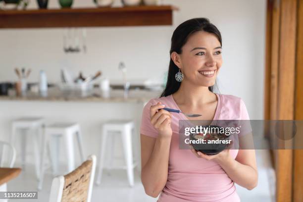 happy woman at home eating a parfait for breakfast - women yogurt stock pictures, royalty-free photos & images