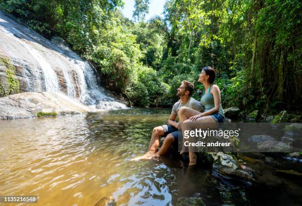 un par de excursionistas mirando una hermosa cascada - turismo ecológico fotografías e imágenes de stock