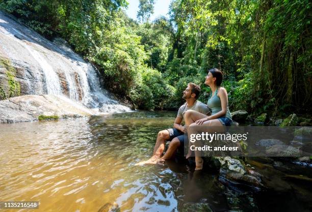 pares de caminhantes que olham uma cachoeira bonita - empreendimento turístico - fotografias e filmes do acervo