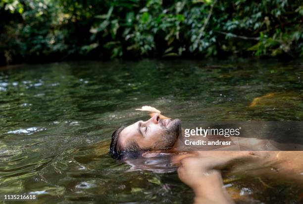 happy man ontspannen en zweven in het water - drijven stockfoto's en -beelden