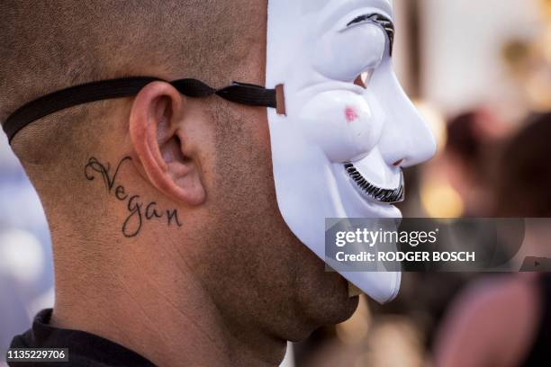 Man with a tatoo reading "Vegan" wears a Guy Fawkes mask as he takes part in the "Global March for Elephants and Rhinos" to save elephants and rhinos...