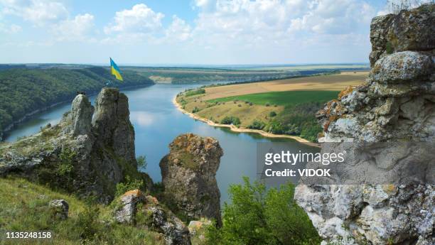flagge der ukraine auf einem felsen mit panoramablick auf die felder und den see. - ukraine landscape stock-fotos und bilder