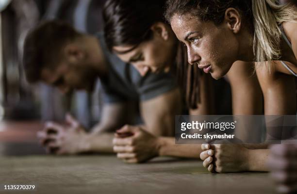 zweterige vrouwelijke atleet in een plank positie met haar vrienden in een sportschool. - plank exercise stockfoto's en -beelden