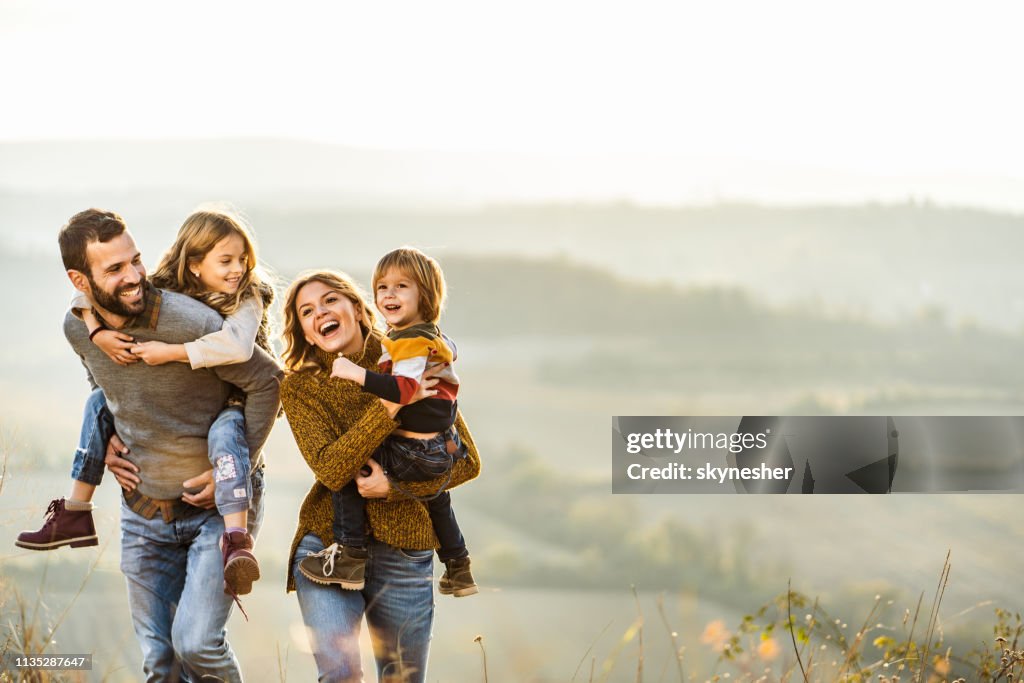 Giovane famiglia felice che si gode in autunno una passeggiata su una collina.