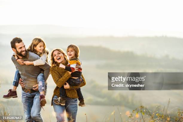 jonge gelukkige familie genieten in de herfst lopen op een heuvel. - happiness stockfoto's en -beelden