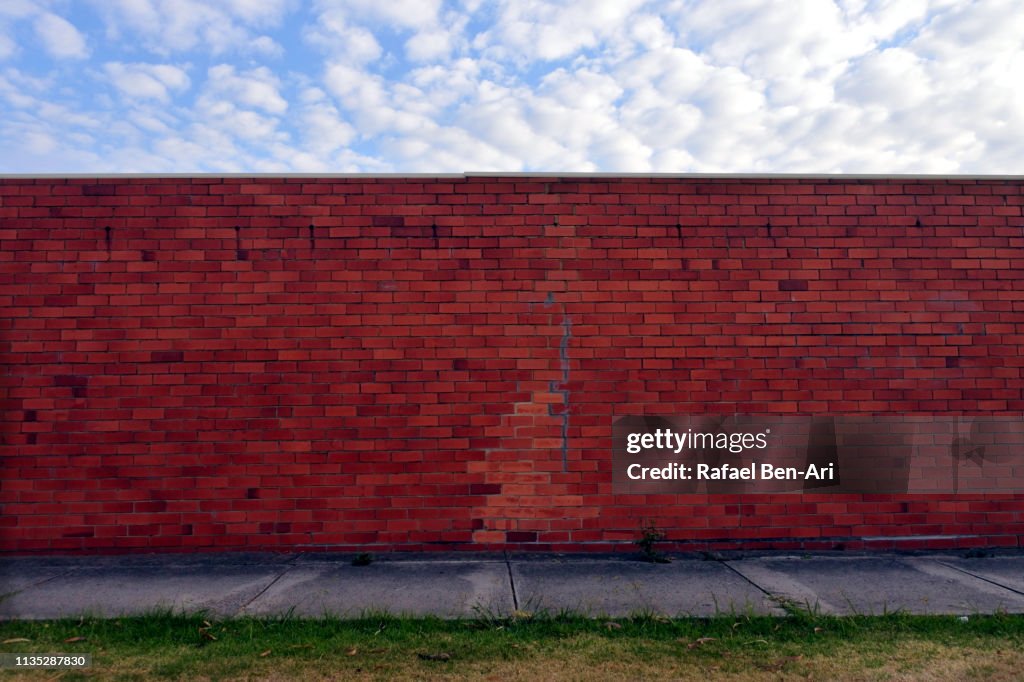 Brick wall under a cloudy sky in urban city sidewalk