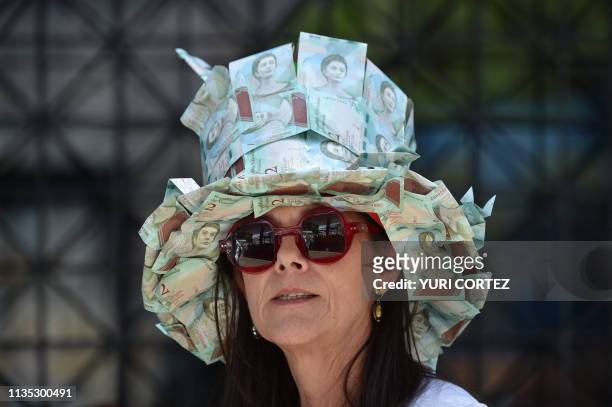 Supporter of Venezuelan opposition leader and self-proclaimed interim president Juan Guaido wears a hat make of Bolivar banknotes during a demo in...