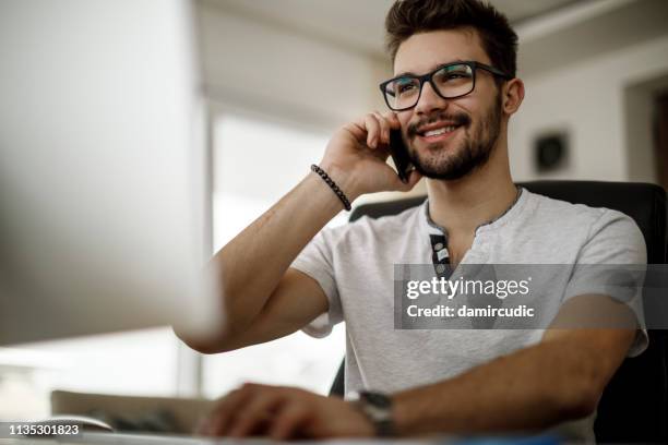 hombre joven hablando por teléfono en casa - boy computer smile fotografías e imágenes de stock