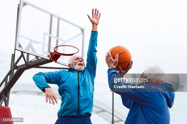 senior brothers playing basketball - old brother stock pictures, royalty-free photos & images