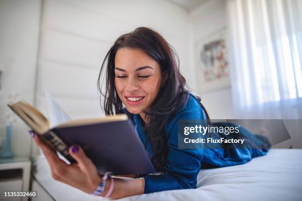 beautiful girl spending a sunday morning reading a book - silk pajamas stock pictures, royalty-free photos & images