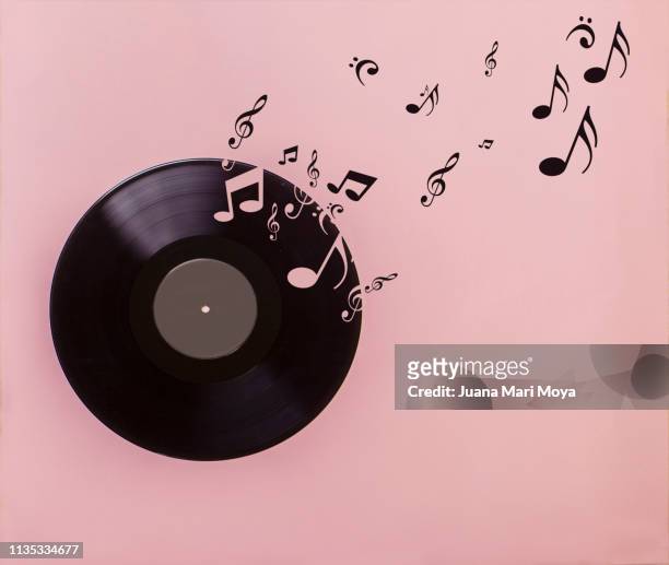 vinyl record on pink background. several musical notes are born of the vinyl record - musica fotografías e imágenes de stock