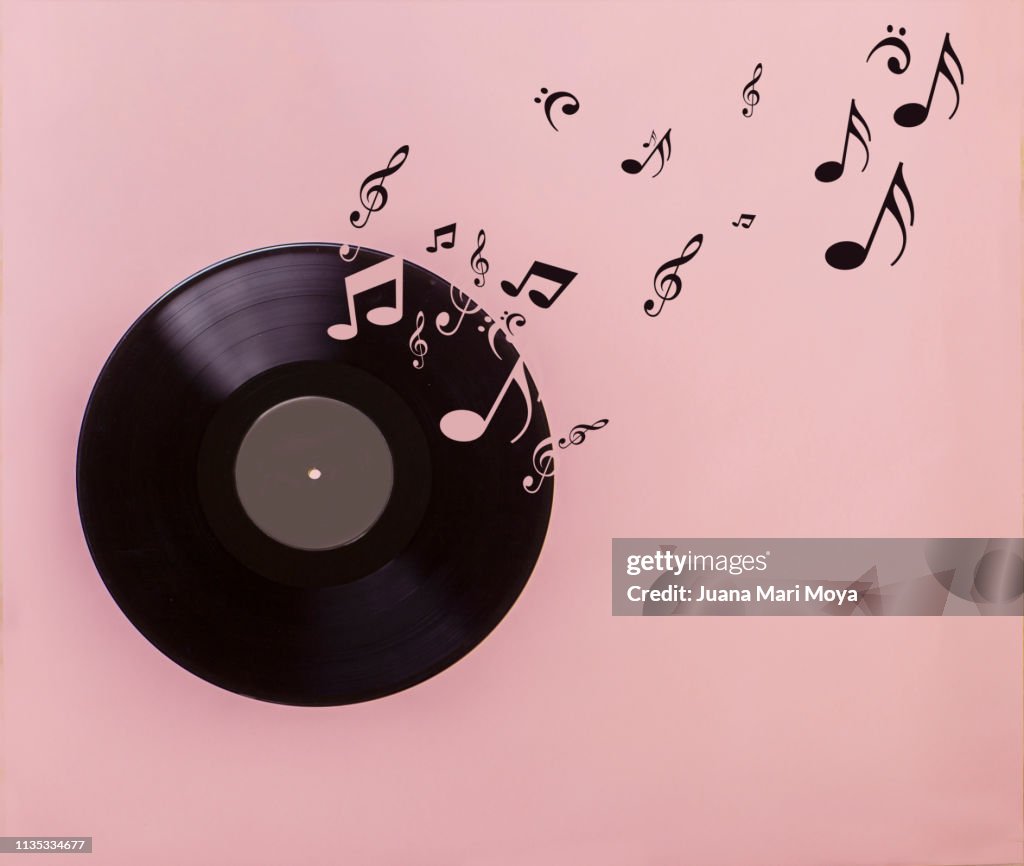 Vinyl record on pink background. Several musical notes are born of the vinyl record