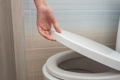 The hand closes or opens the toilet lid