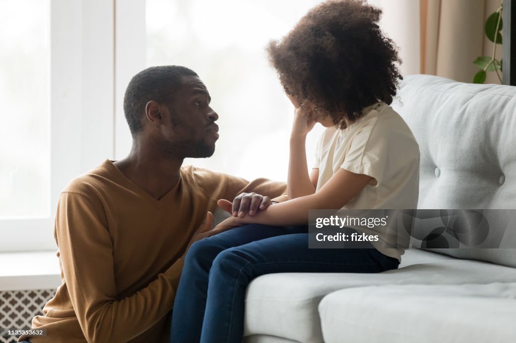 Loving african dad comforting crying kid daughter showing empathy