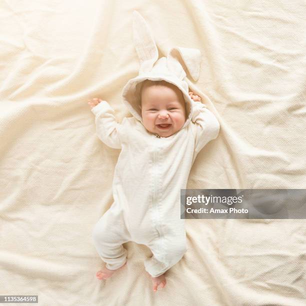 having fun on easter day. baby boy wearing bunny costume with ears smiling. - baby background stock pictures, royalty-free photos & images