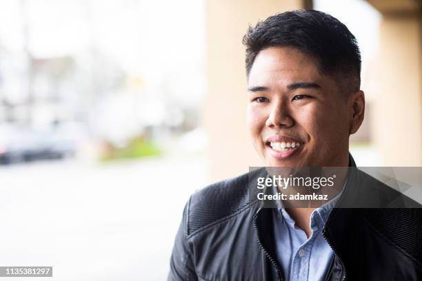 portret van een jonge man buiten glimlachend - testimonial stockfoto's en -beelden